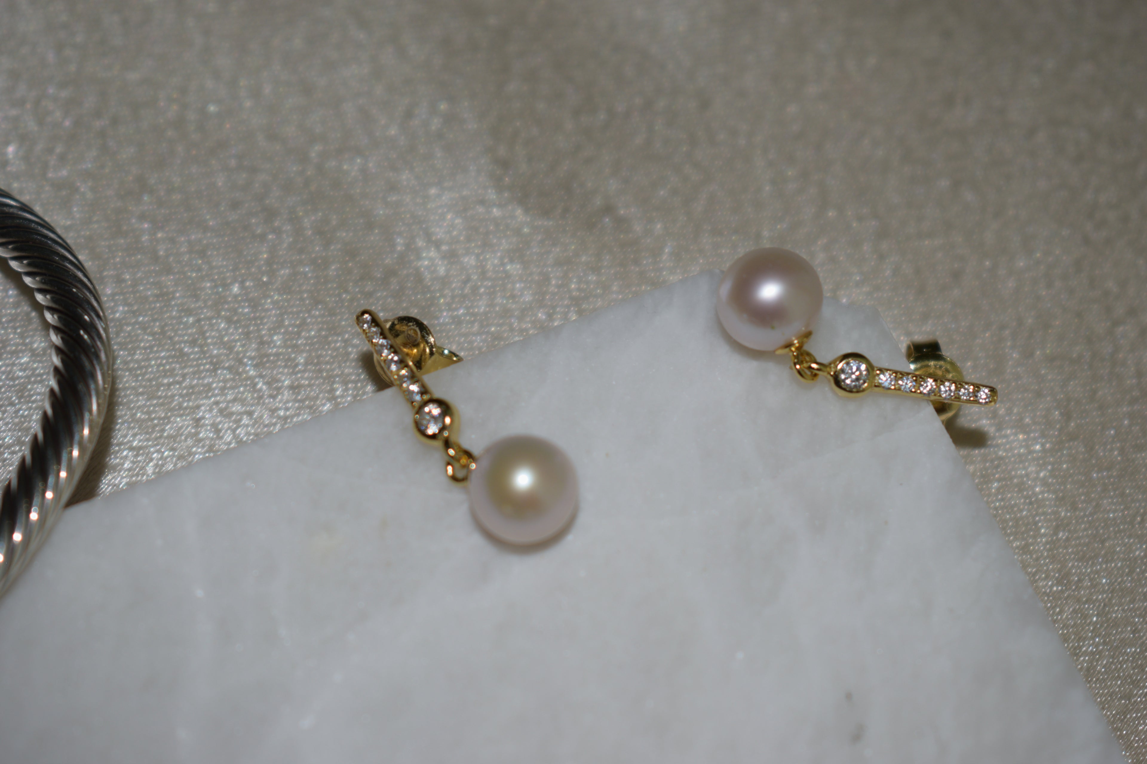 Pearl earrings with gold accents on a textured surface